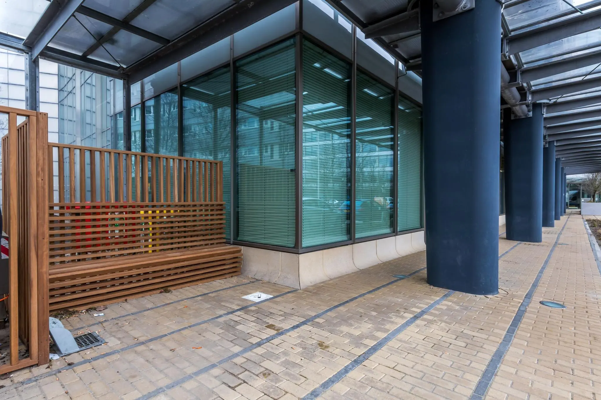 Glazen hoekgevel van een modern kantoorpand aan de Vliegend Hertlaan met overkapping en houten afscheiding.